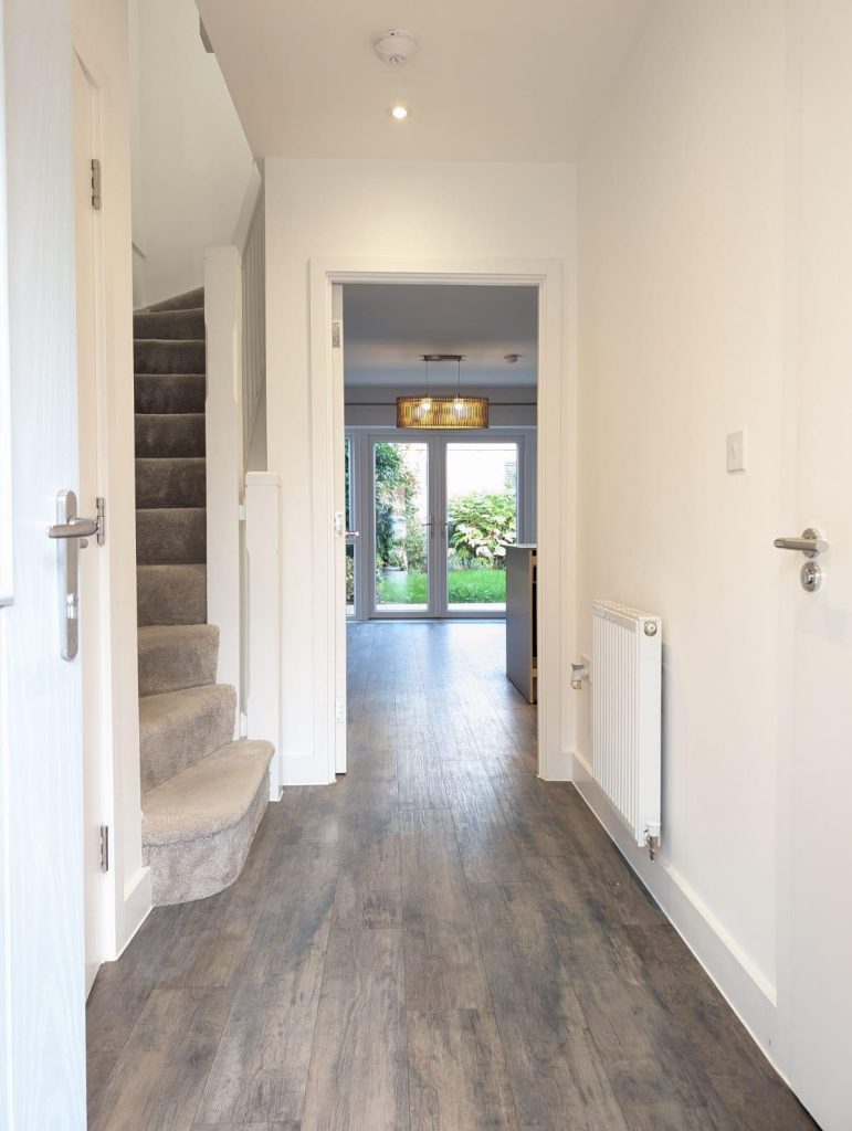 A hallway featuring polished wooden floors and bright white walls, creating a clean and spacious atmosphere.