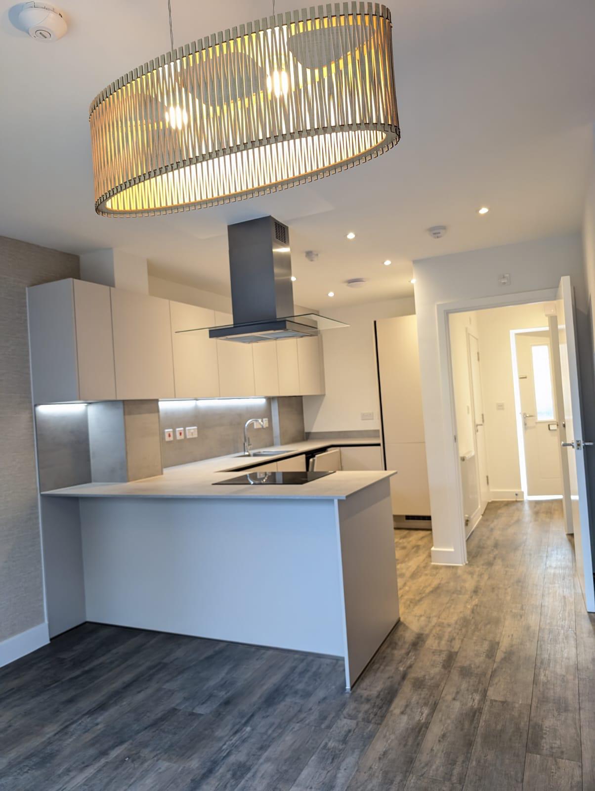 A spacious kitchen featuring a large island and an elegant light fixture hanging above.
